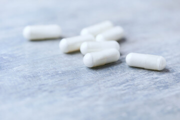 Beta-alanine capsules. Bodybuilding food supplements on wooden background. Soft focus. Close up. Copy space.	