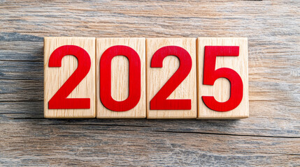Fototapeta premium Wooden cubes displaying year 2025 in bold red numbers on rustic wooden surface evoke sense of anticipation and new beginnings