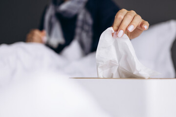 Woman sick , lying in bed with runny nose using napkins