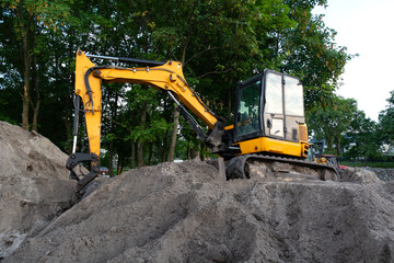 Yellow Excavator at Work in a Green Area - Side View