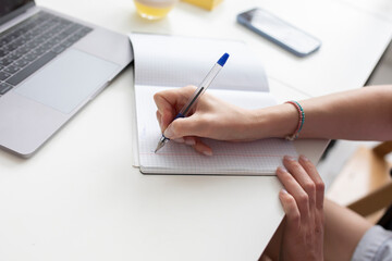 Close-up shot of female hands writing in a notebook. Education and online learning concept