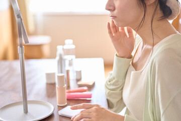 自宅の部屋でスキンケアをしている若い女性。