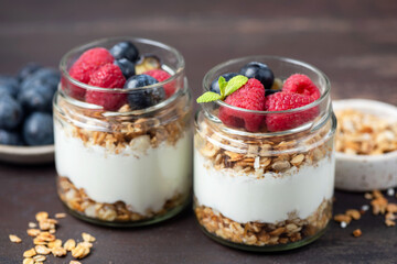 Layered yogurt granola parfait with berries on a wooden table background, closeup view