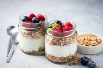 Layered yogurt granola parfait with berries on a wooden table background, closeup view