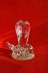 the symbol of the new year 2025. crystal snake figurine on a red background. a transparent cobra. Happy New Year. background for decoration. winter holiday.