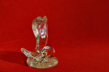 the symbol of the new year 2025. crystal snake figurine on a red background. a transparent cobra. Happy New Year. background for decoration. winter holiday.