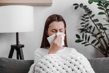 Unhealthy caucasian female blowing nose, coughing or sneezing in tissue. Cold and fever concept....