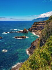 Fototapeta premium Dramatic coastal cliffs with turquoise waters and rocky formations along Madeira's rugged shoreline.