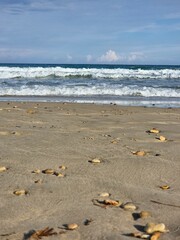 Ein flacher Blick über den Sandstrand, der von Kieselsteinen gesäumt wird und in das Meer führt....