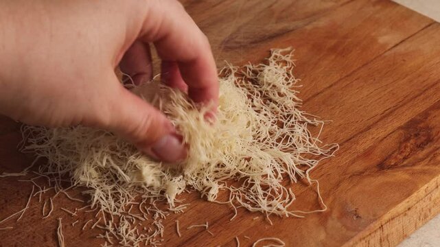 Finely shredded phyllo dough on wooden surface. close-up of delicate strands of phyllo dough, commonly used in preparing traditional desserts like kataifi, kunafa, Dubai chocolate. raw kataifi dough