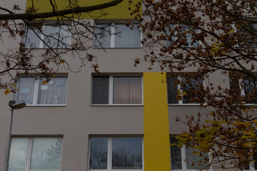 This residential building prominently features a distinctive yellow element and is surrounded by lush trees