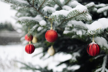 Happy New Year Christmas tree decorates with yellow red glass ball on branch snow outdoors for family winter holiday. Festival mood. Noel. 