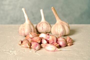 Fresh garlic bulbs with stems intact, arranged on a light, textured surface, showcasing their natural rustic appearance.