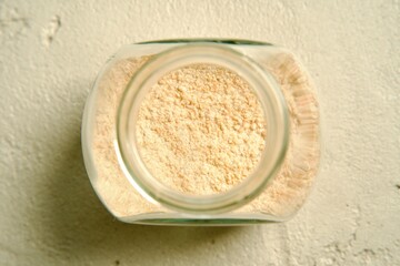Ground garlic neatly stored in a spice jar, placed on a light surface.