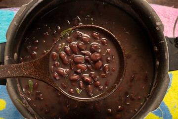 Black Beans Cooked in the pressure cooker with a bean ladle on a wooden desk