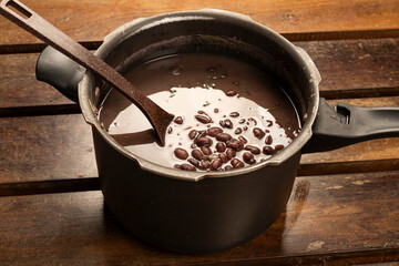 Black Beans Cooked in the pressure cooker with a bean ladle on a wooden desk