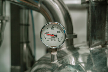 Steel pressure gauge of industrial equipment Water pressure is measured using an antique dial and a worn valve.
