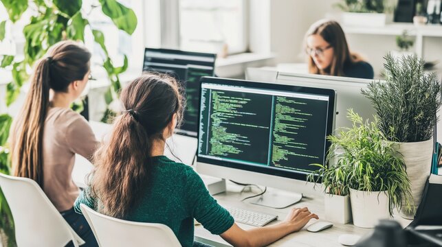 Female software developers coding in bright modern office, teamwork and innovation in tech industry, green workspace with plants and collaboration