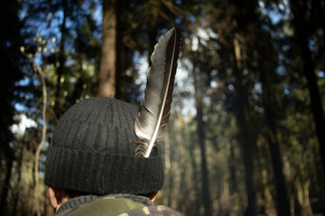 Raven feather in a hat. Black feather of a bird. Indian in the forest.