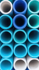 Cylindrical PVC pipes in various shades of blue and white stacked together, showcasing their smooth surfaces and vibrant colors. arrangement creates visually appealing pattern