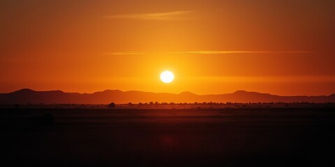 Tranquil sunset image captures golden hues over distant mountains, highlighting nature's beauty.