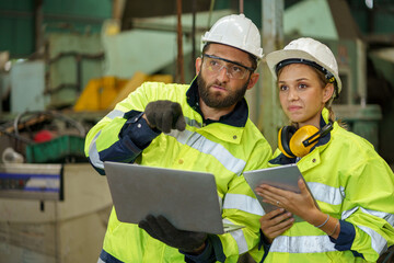 caucasian industrial Engineer manager man wearing eyeglass and helmet discussion with mechanic worker woman while using digital tablet checking industry manufacturing large factory . inspection