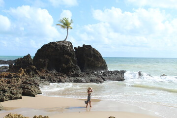 mulher na praia com pedra do coqueiro ao fundo em tambaba, conde, paraíba 