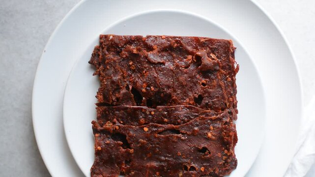 Overhead view of Nigerian kilishi on a white plate, top view of nigerian spicy beef jerky, flatlay of dried beef suya