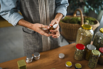 Adult man herbalist prepare natural oils in a bottle with pipette