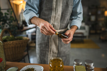 Adult man herbalist prepare natural oils in a rustic kitchen setting