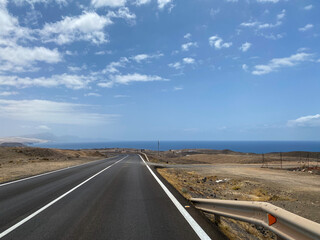 Empty road in a sandy desert ocea side