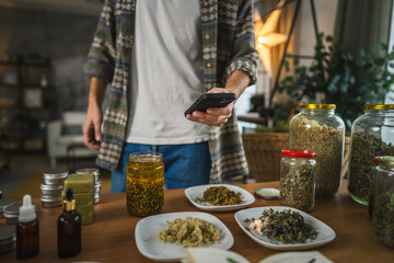 close up of adult man take a photo of herbs from plate with cellphone