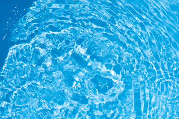 Fototapeta premium Blue water with ripples on the surface. Defocus blurred transparent blue colored clear calm water surface texture with splashes and bubbles. Water waves with shining pattern texture background.