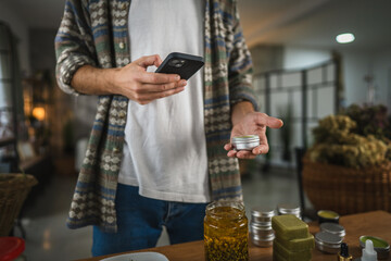 adult man take a photo of natural salve with cellphone at workshop
