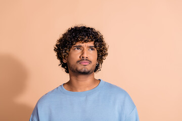 Photo of dreamy suspicious guy dressed blue sweatshirt looking empty space isolated beige color background