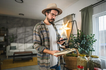 adult man take a photo of recipe from book with cellphone at workshop