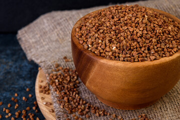 Buckwheat in wooden bowl on dark background.
