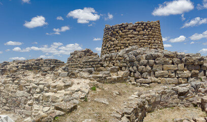 Majestic ruins of nuraghe Piscu in sardinia, italy, stand tall against a vibrant blue sky,...