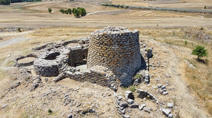 Majestic ruins of nuraghe Piscu in sardinia, italy, stand tall against a vibrant blue sky,...