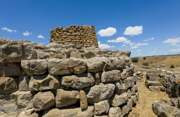Majestic ruins of nuraghe Piscu in sardinia, italy, stand tall against a vibrant blue sky,...