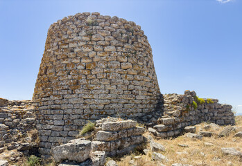 Majestic ruins of nuraghe Piscu in sardinia, italy, stand tall against a vibrant blue sky,...