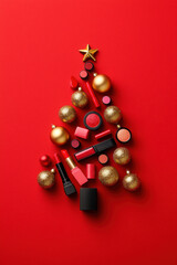 Festive arrangement of lipsticks and ornaments forming a Christmas tree on a vibrant red background, perfect for holiday themes.