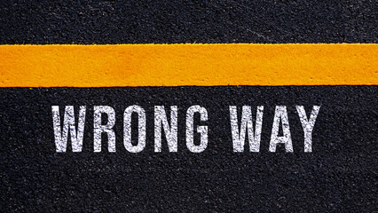Wrong way, wrong way text written and yellow line on asphalt road ground.