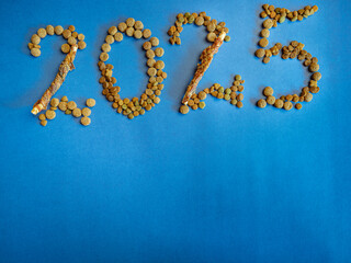 Background with the text 2025, text built from dry pet food. Graphic resources for pet shop promotion.
