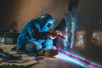 Welders at work in metal argon industry, welding metal plate tank construction close up wear protective gloves and mask in side confined