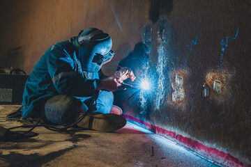 Welders at work in metal argon industry, welding metal plate tank construction close up wear protective gloves and mask in side confined