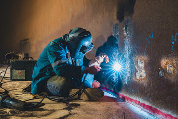 Welders at work in metal argon industry, welding metal plate tank construction close up wear protective gloves and mask in side confined