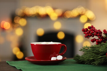 Tasty cocoa with marshmallows in cup and decor on table against blurred Christmas lights, bokeh effect