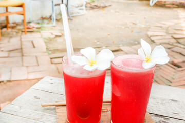 Watermelon smoothie with plumeria flowers, Fresh watermelon juice with ice in a glass,summer refreshing drink in glasses,Slices of watermelon on the table.