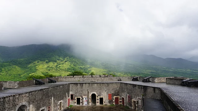 Rain falling over fort, the Brimstone Hill Fortress National Park, made of brick with green jungle and mountain in Saint Kitts